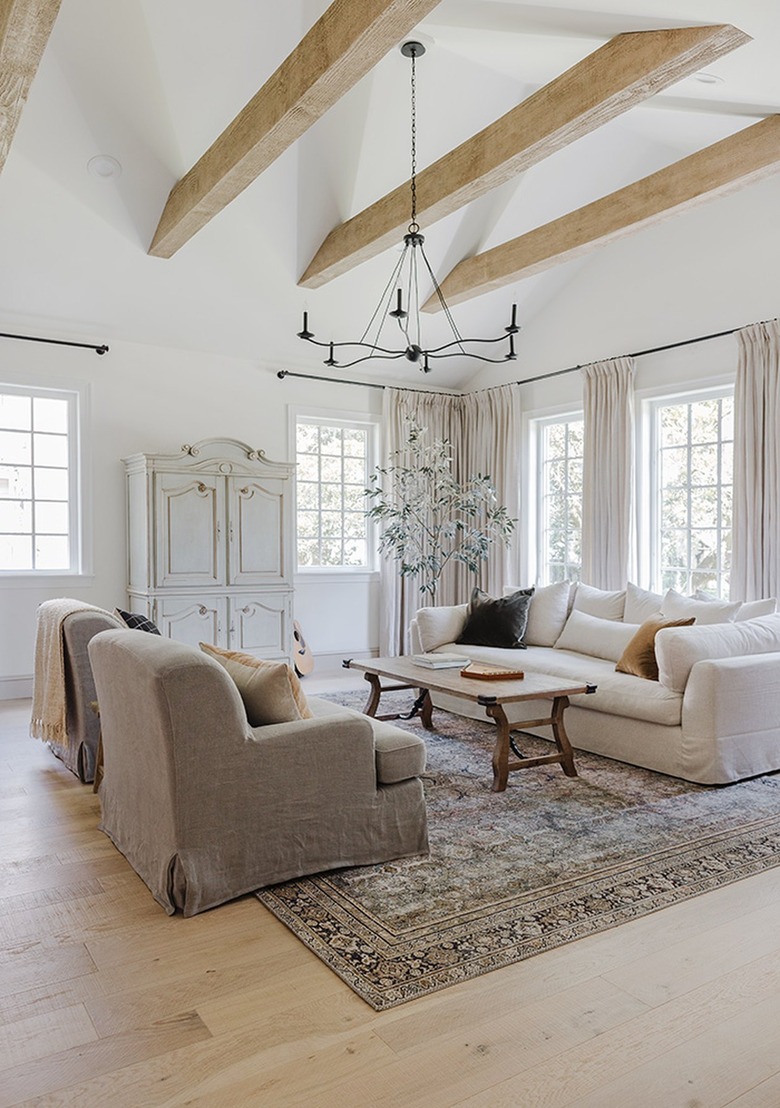 Rustic living room with beamed ceiling and dainty black chandelier.