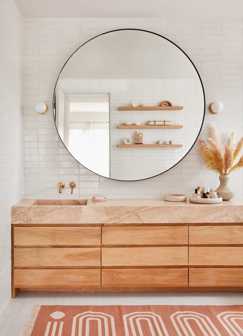 bathroom with large round mirror and pale pink countertop