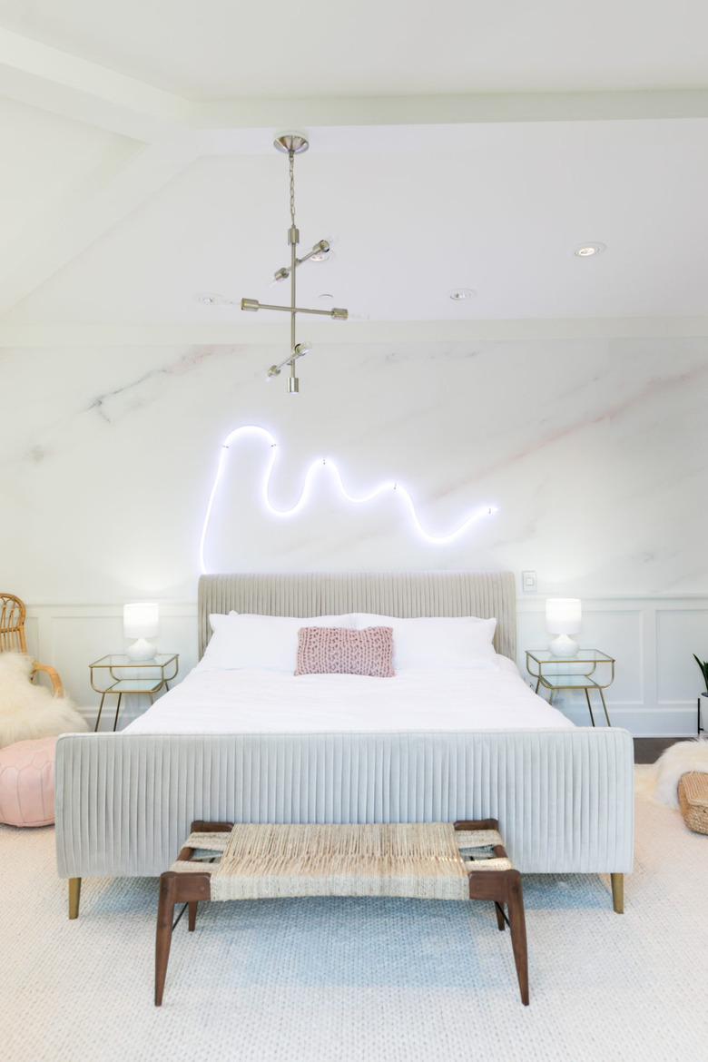 whimsy neon light above the headboard in white bedroom