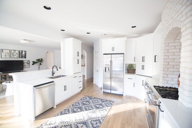 open kitchen with brick wall and white cabinetry