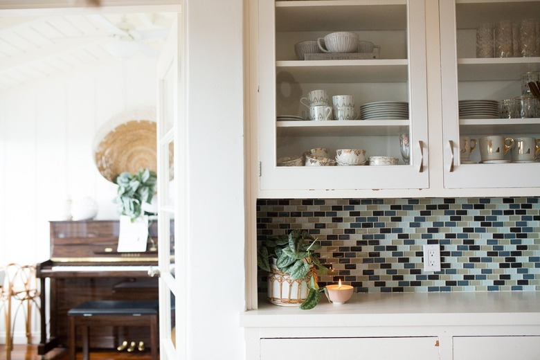 A white kitchen cabinet with dish ware