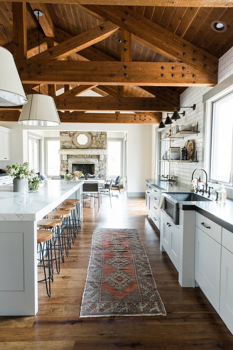 farmhouse kitchen with exposed ceiling beams and runner in front of sink