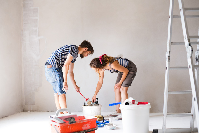 Young couple painting walls in their new house.