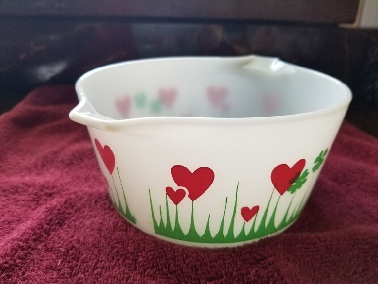 The Lucky in Love Pyrex dish on a red blanket. The dish is a translucent white and features red hearts
