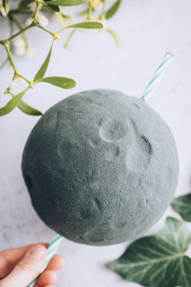 a straw pokes through a green foam floral ball