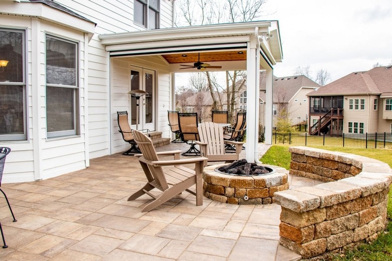A stamped concrete patio with a brick half wall and a matching brick fire pit