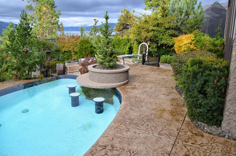 A brown concrete stamped patio with large cut squares and an in-ground swimming pool