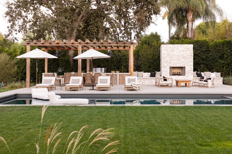 outdoor kitchen next to fireplace and pool