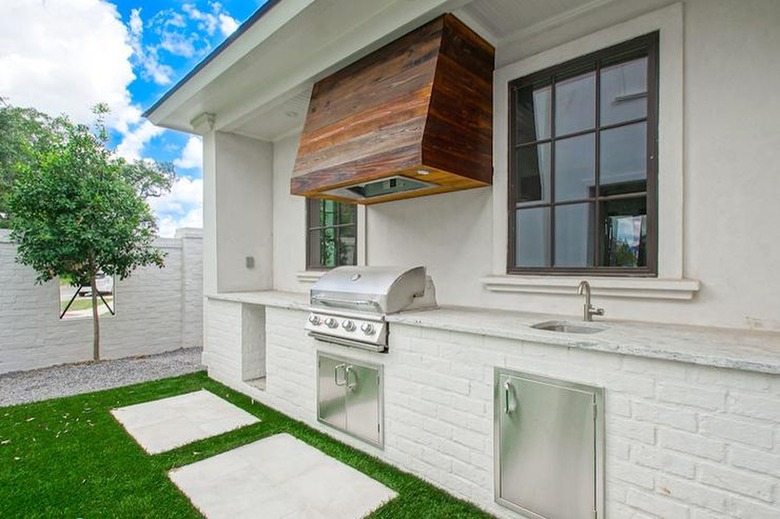white outdoor kitchen with reclaimed wood hood