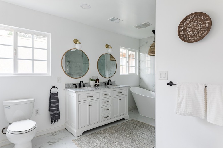 Minimalist white bathroom with large round mirrors