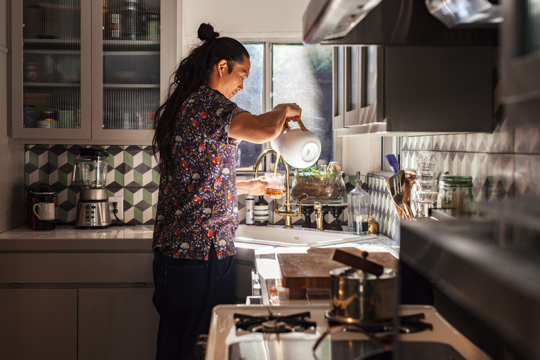 Sato pours tea for himself in the kitchen