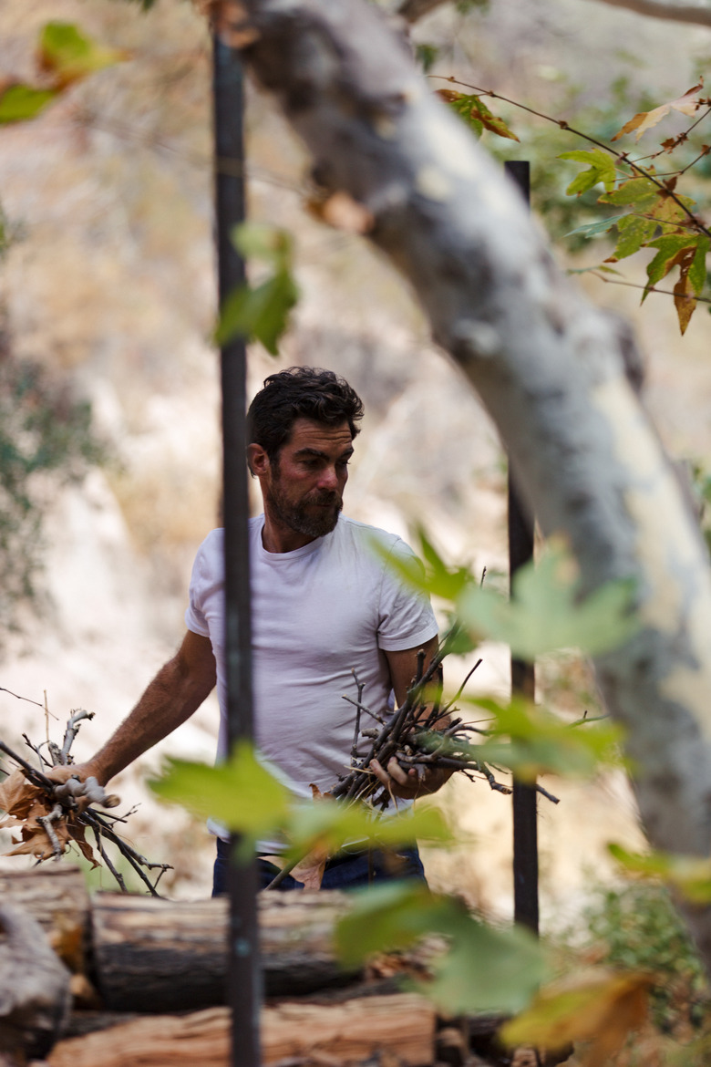 Shot of Mathew gathering wood for the grill's fire