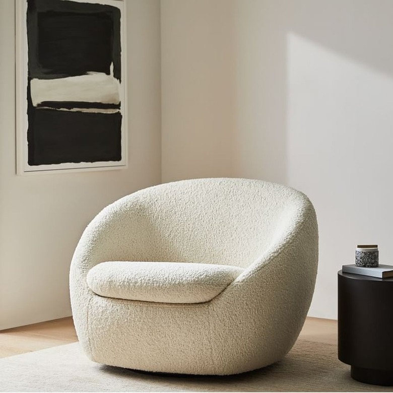 white boucle chair near black and white artwork