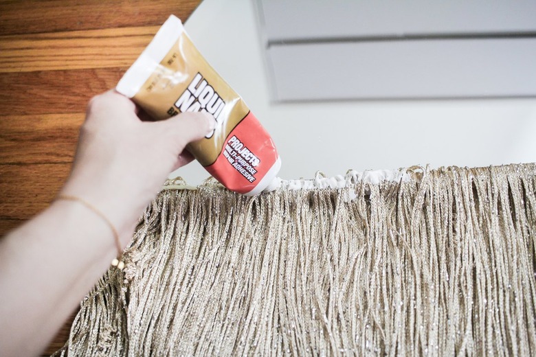 Hand putting glue on curtain fringe and mirror