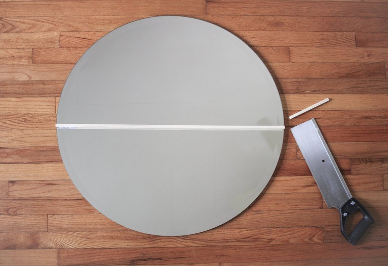 Round mirror with saw and cut wood dowel