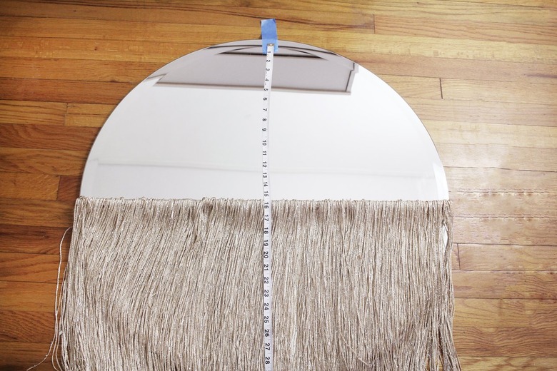 Round mirror with neutral curtain fringe and measuring tape
