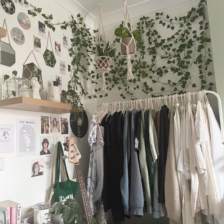 corner of bedroom with clothes rack and gallery wall of small art objects