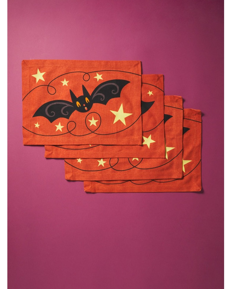 Four orange placements with a large single bat surrounded by yellow stars and thin black loopy lines. They are on a plum-colored background.