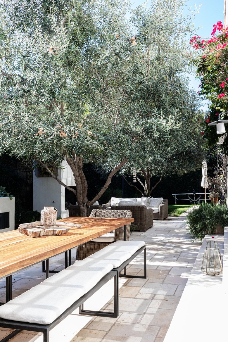 A wood table with benches on a patio surrounded by trees