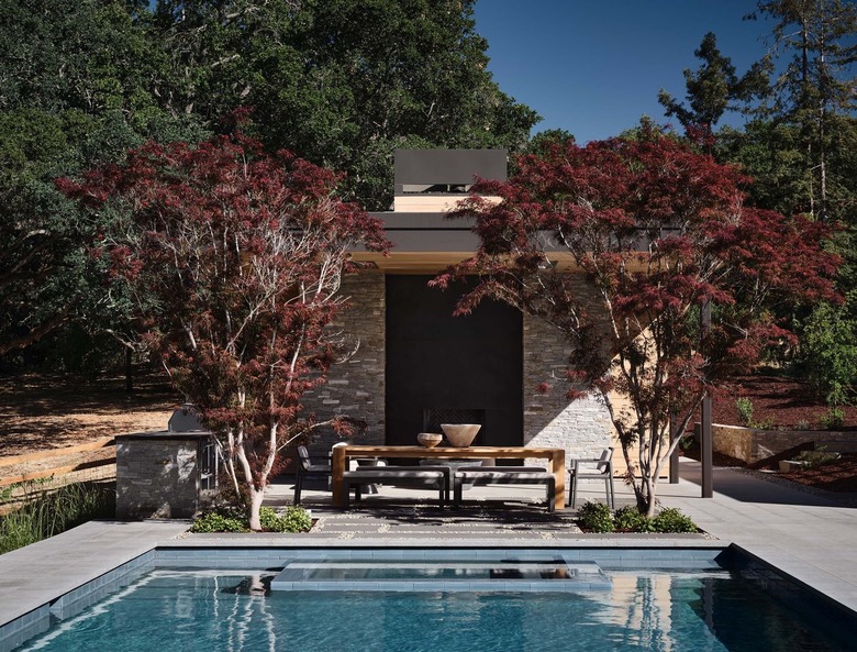 Minimalistic outdoor dining setup overlooking pool and nature