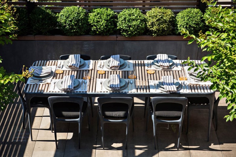 Simple tablescape at an outdoor dining setup surrounded by greenery