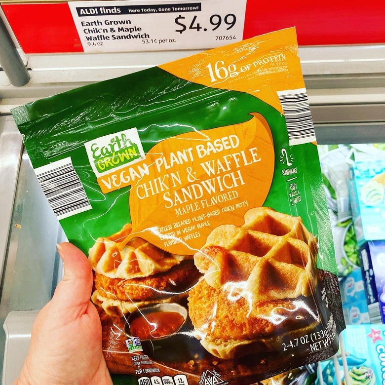 Hand holding the new Earth Grown's Plant-Based Chik'n & Waffle Sandwich package in Aldi store