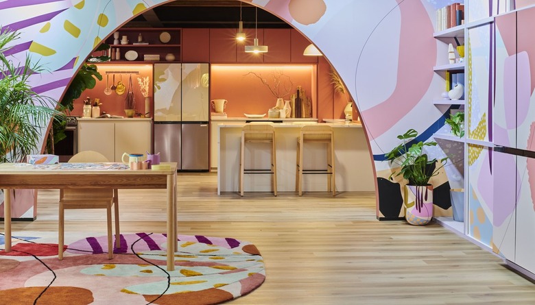 A colorful and patterned room with an arched open hall leading into a kitchen with hardwood floors.