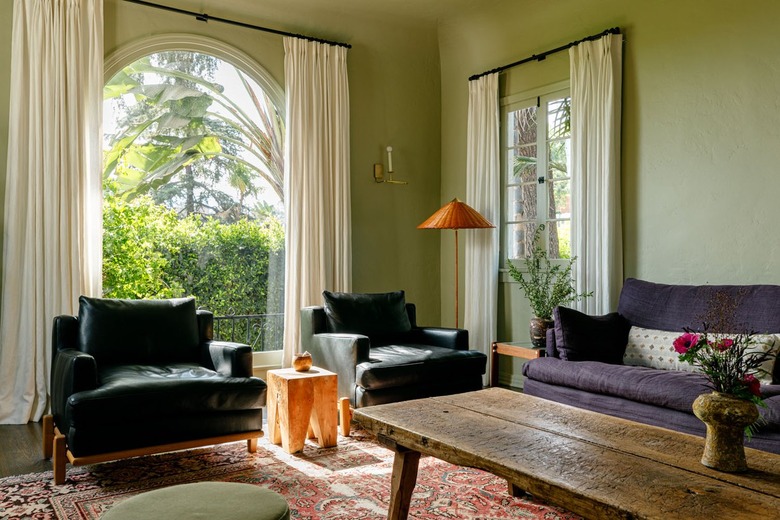 moody green living room with ivory curtains