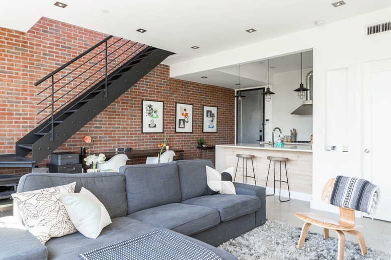 Black metal staircase against brick wall with wood table