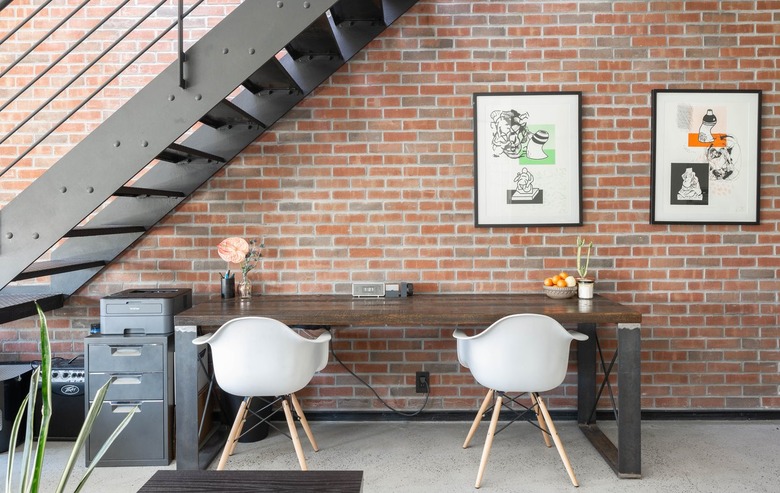 Black metal staircase against brick wall with wood table