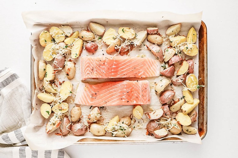 Salmon filets and sliced potatoes on a baking sheet