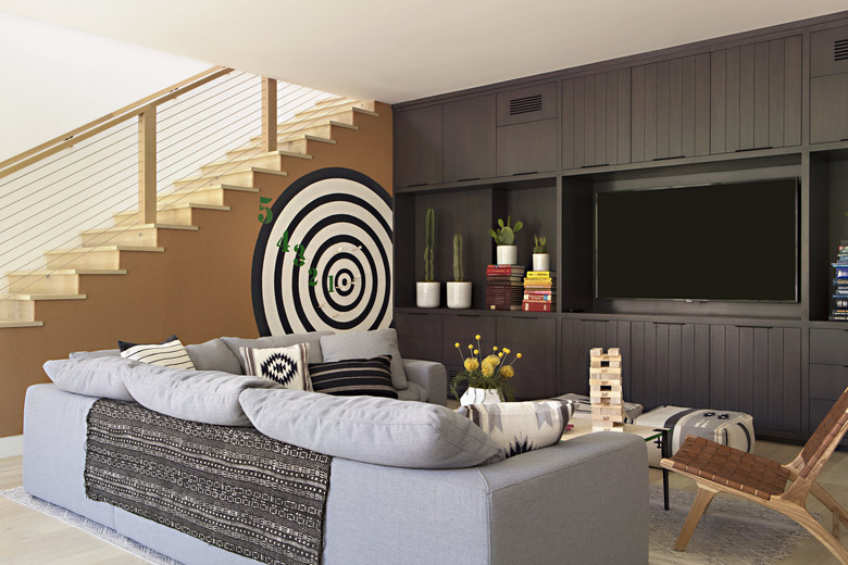 basement furniture with gray sectional, tv, and dart board