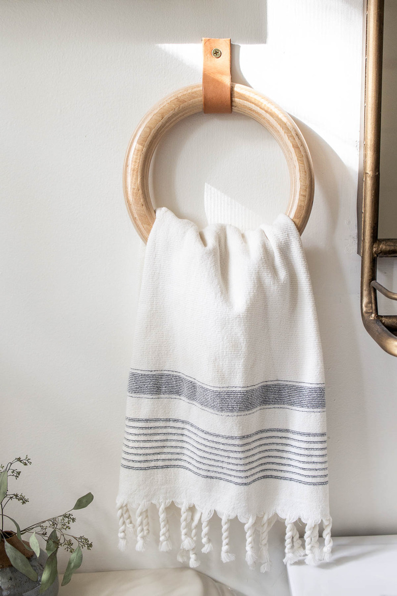 DIY wood and leather towel ring hanging on bathroom wall with Turkish hand towel