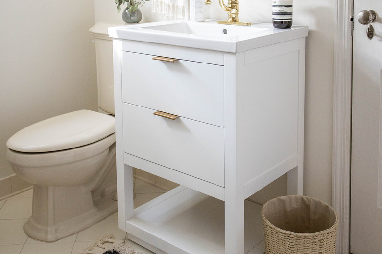 White bathroom sink vanity with brass handles