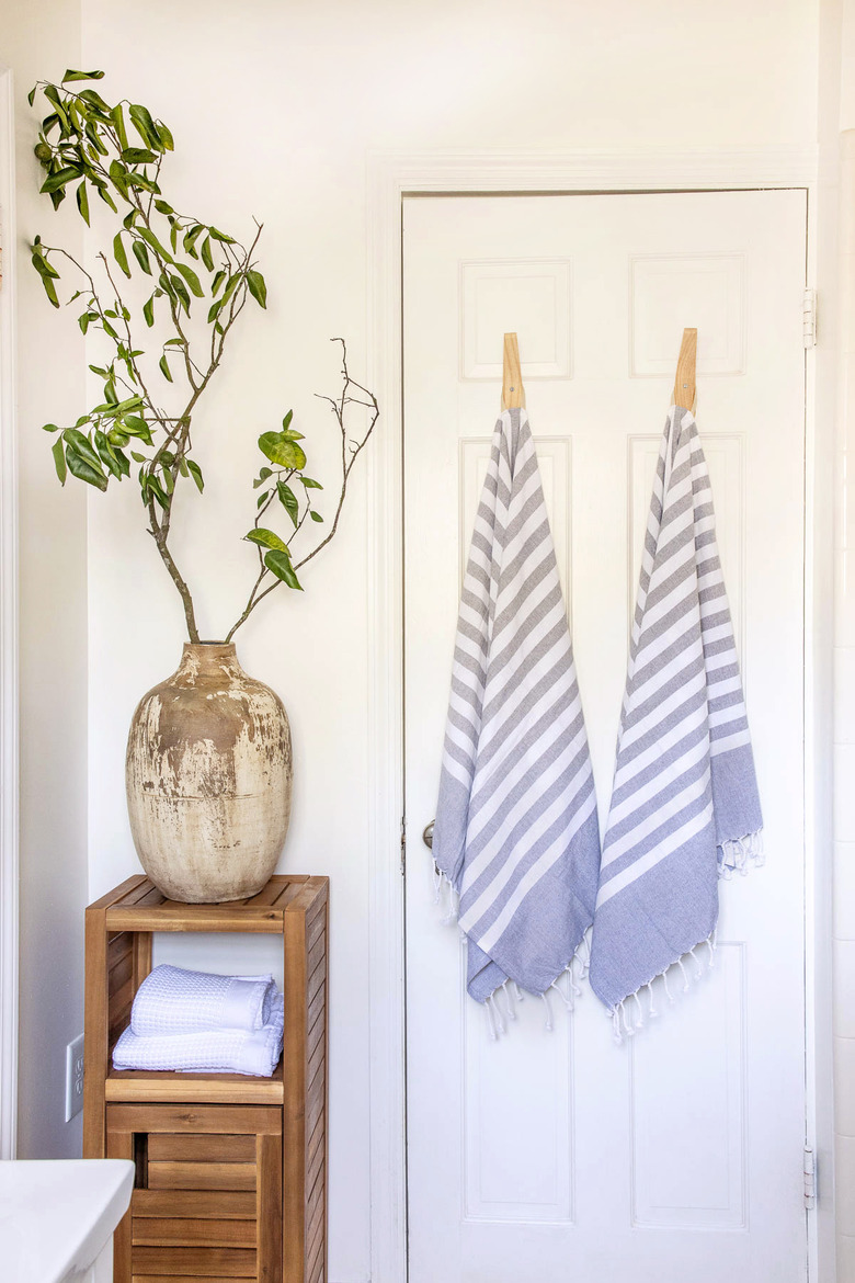 Ceramic jug vase filled with branches on top of wooden bath cabinet