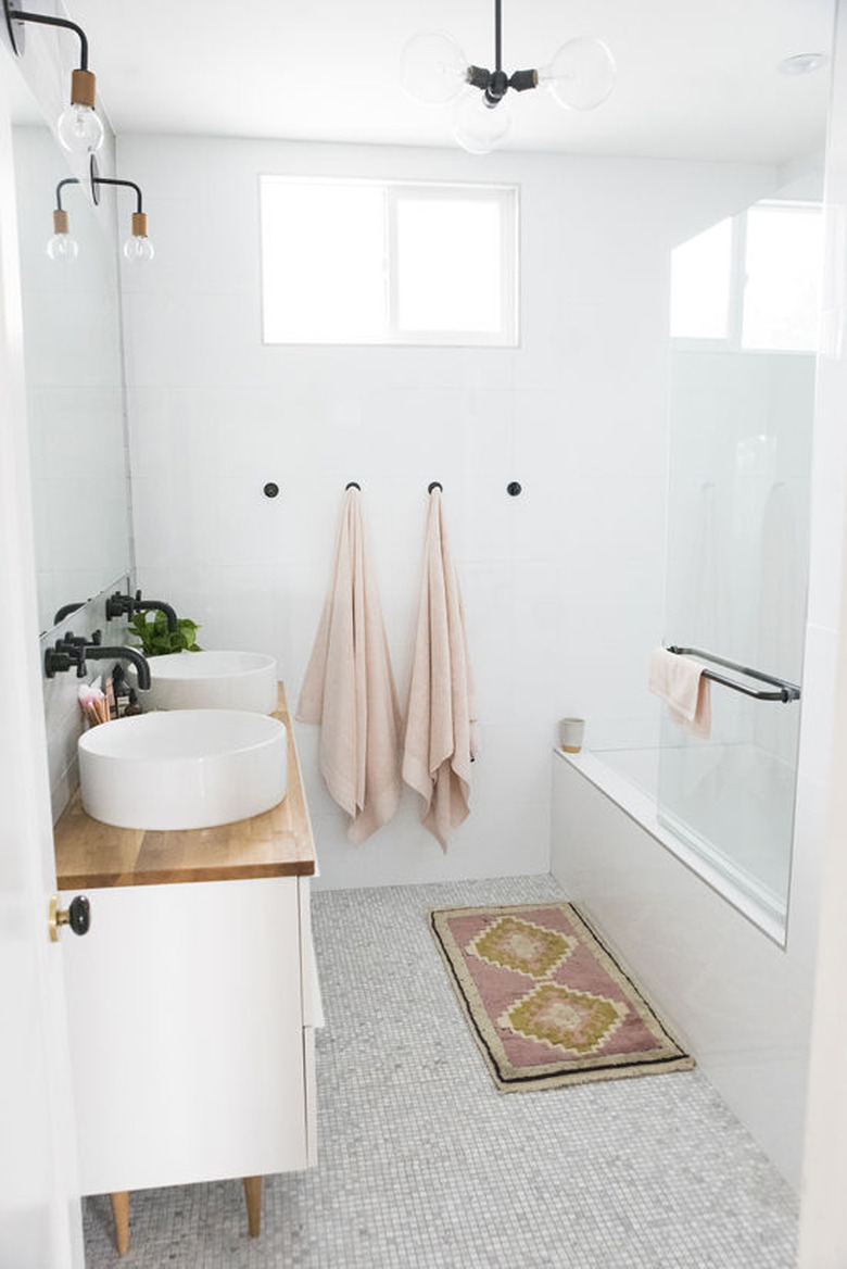 bathroom rug idea in white and pink bathroom with wood countertops and vessel sinks