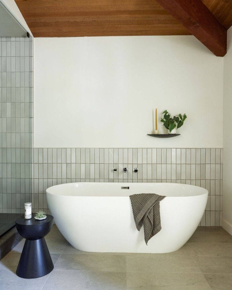 Gray and white minimalist bathroom with wood accents and ceiling and small shelf behind the bathtub