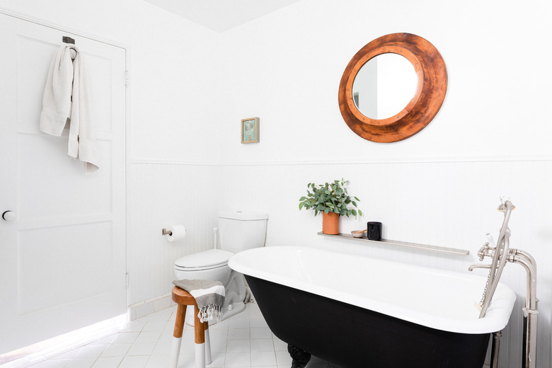 white bathroom with toilet and stand-alone black claw-foot tub