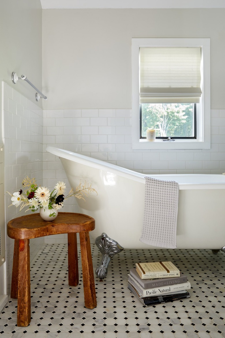 bathtub near wood stool and books on the floor