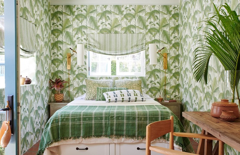 A green and white maximalist bedroom with palm tree wallpaper