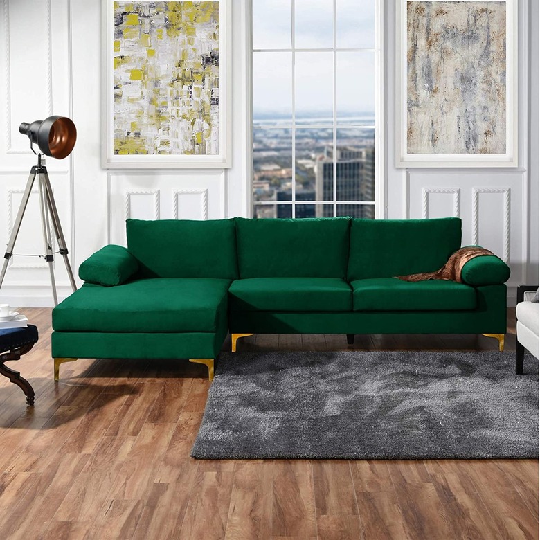 Green couch in room with wooden floor accessorized with a gray rug