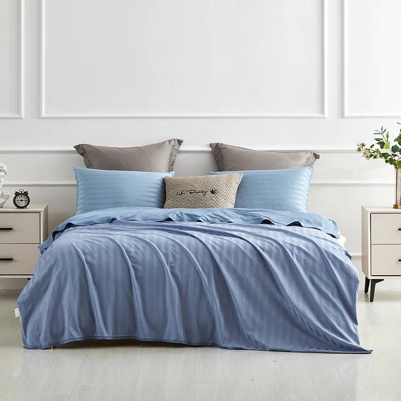 A bed with a blue blanket and pillows