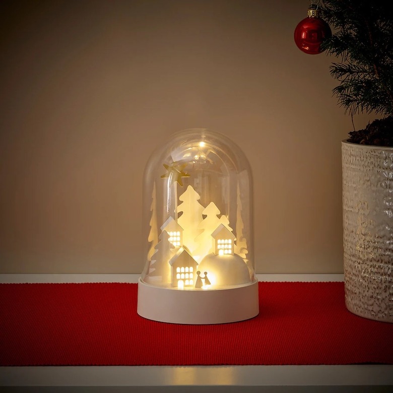 A clear dome with a small white holiday village that lights up inside.