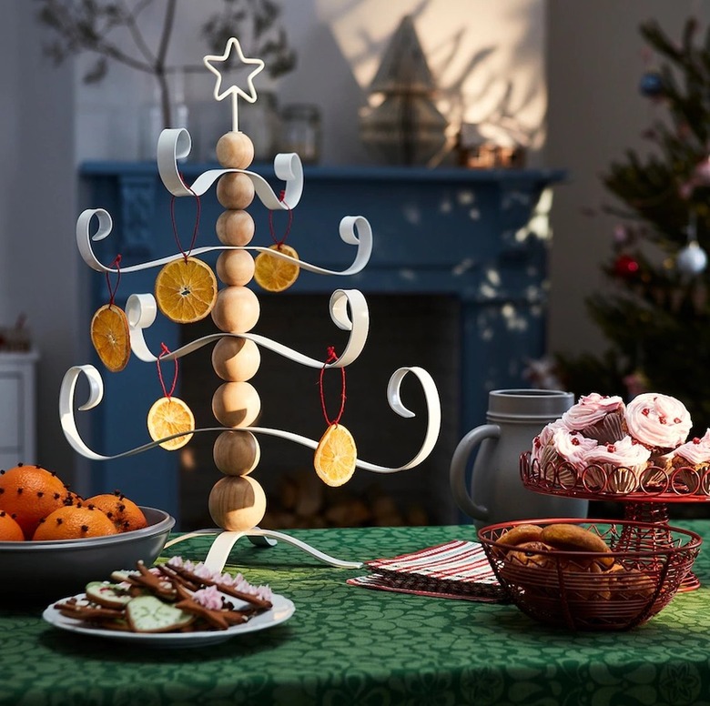 A Christmas tree decoration featuring wood balls stacked as a trunk and white metal branches along with a white metal star on top.