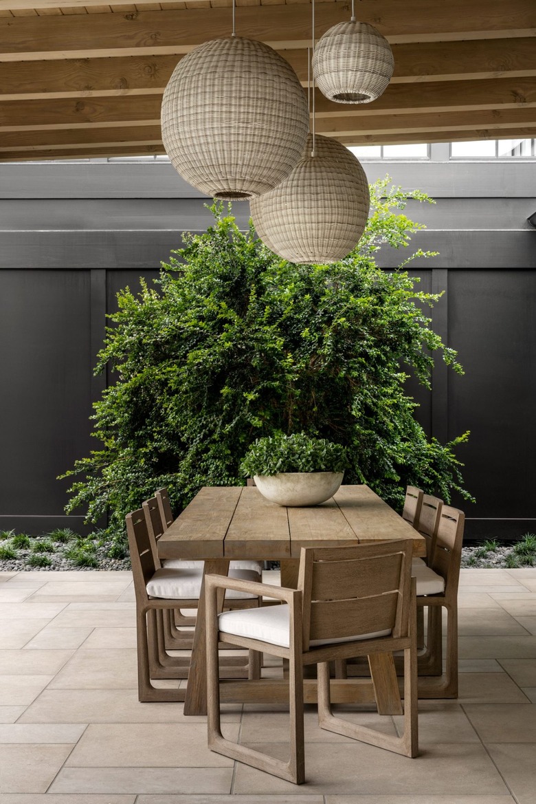 outdoor dining table with round woven lanterns hanging above