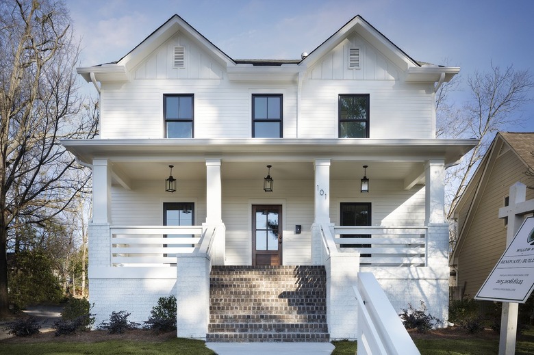 white two-story house with pendant lanterns hanging over door and two windows