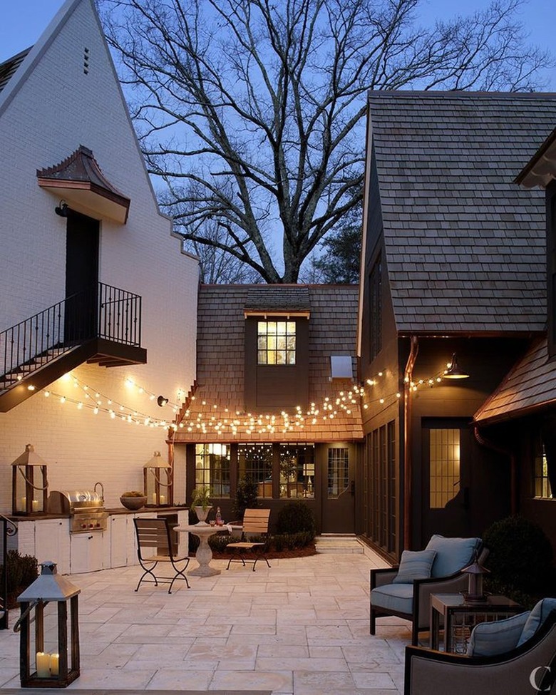 outdoor kitchen and dining area with string lights hung overhead