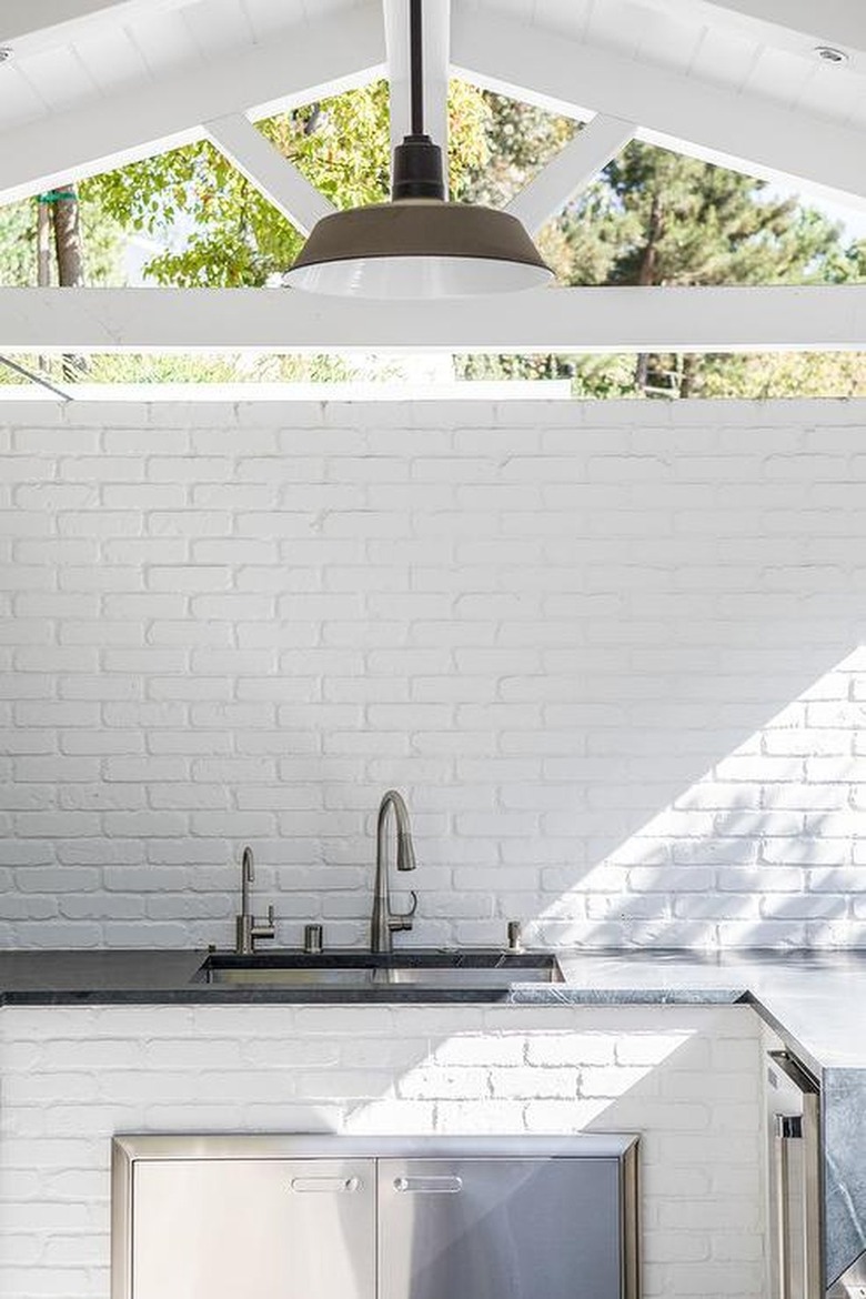 covered outdoor kitchen with pendant light hanging over sink