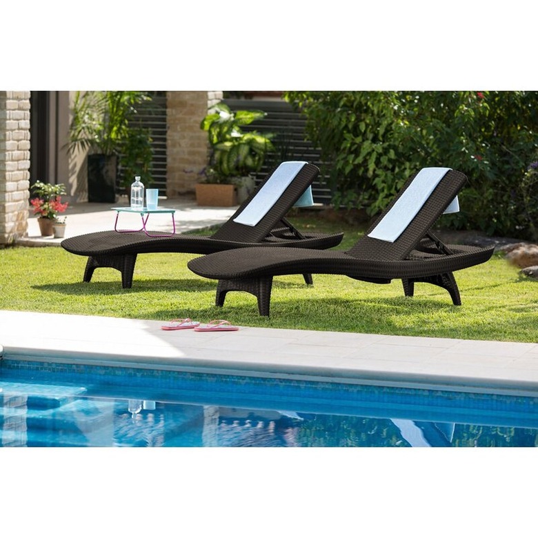 Brown outdoor lounge chairs on grass by pool