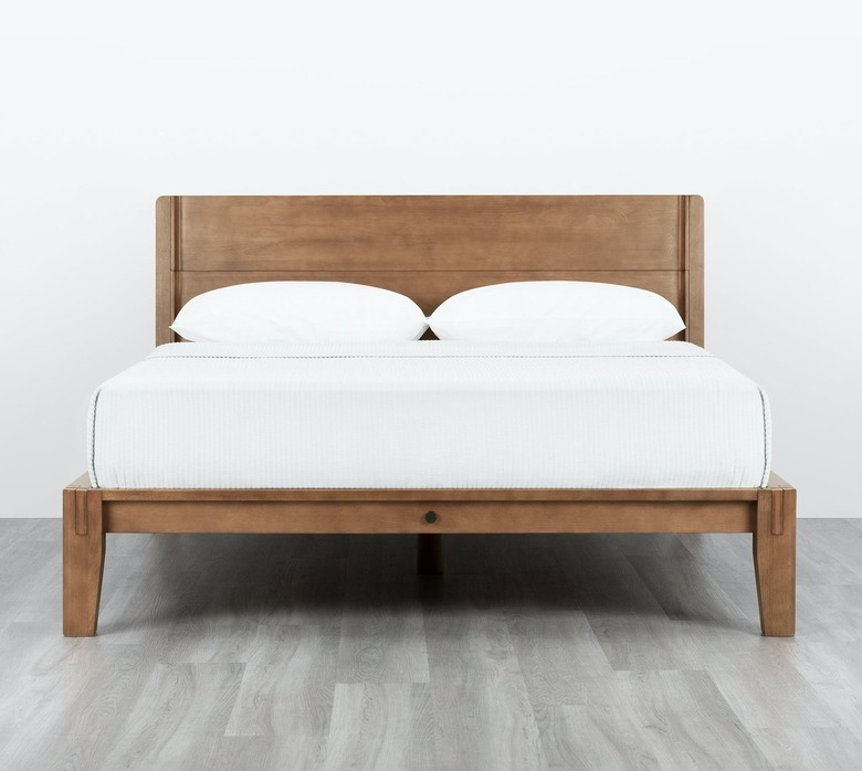 Thuma The Bed in Walnut with white sheet and pillows.